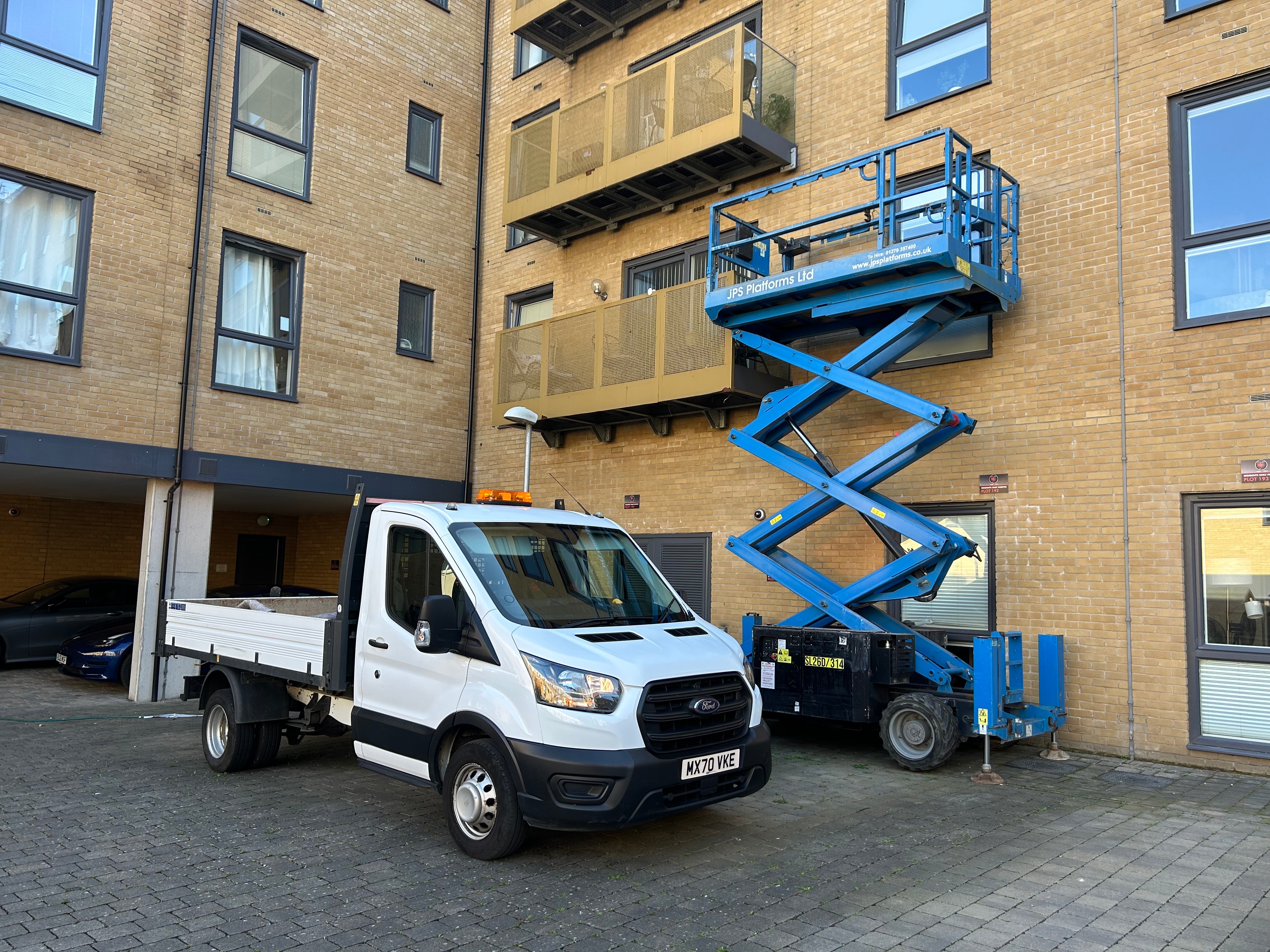 Professional facilities maintenance equipment including scissor lift and service vehicle at modern building
